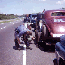 Bob Melnick and Pete Hamilton changing a tire on the side of the road