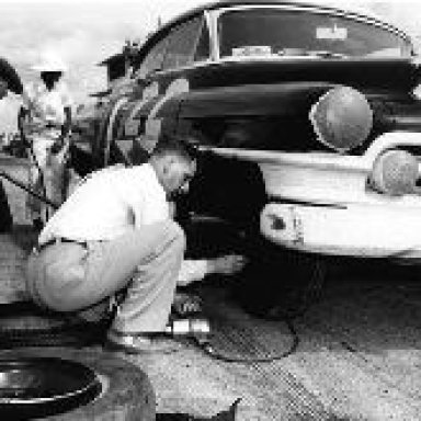 Raymond Parks changing tire on Red Byron's Cadillac - Darlington 1950